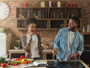 Happy black couple preparing dinner together in modern kitchen