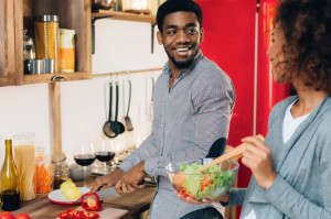 Young african-american couple preparing salad in kitchen
